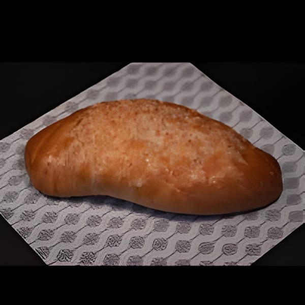 A golden-brown Colombian pan de bono, a type of cheese bread, rests on a patterned napkin.