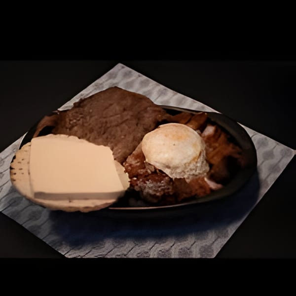 Colombian dish with a large piece of meat, a fried egg, and a slice of cheese on a plate.