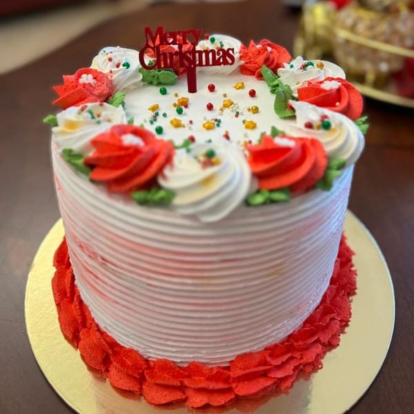 A festive Christmas cake from Los Panes Bakery, decorated with red and white frosting, sprinkles, and a "Merry Christmas" topper.